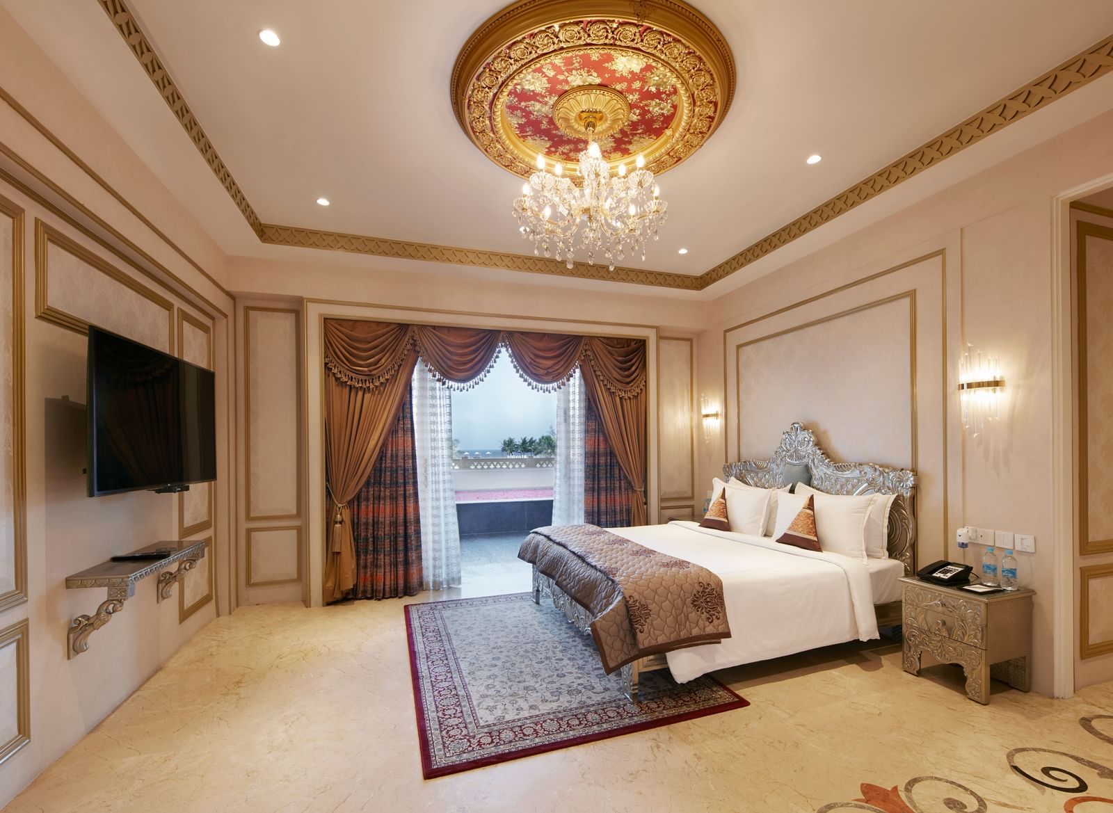 Bedroom with a regal gold-accented ceiling and a comfy double bed with red cushions - Kaldan Samudhra