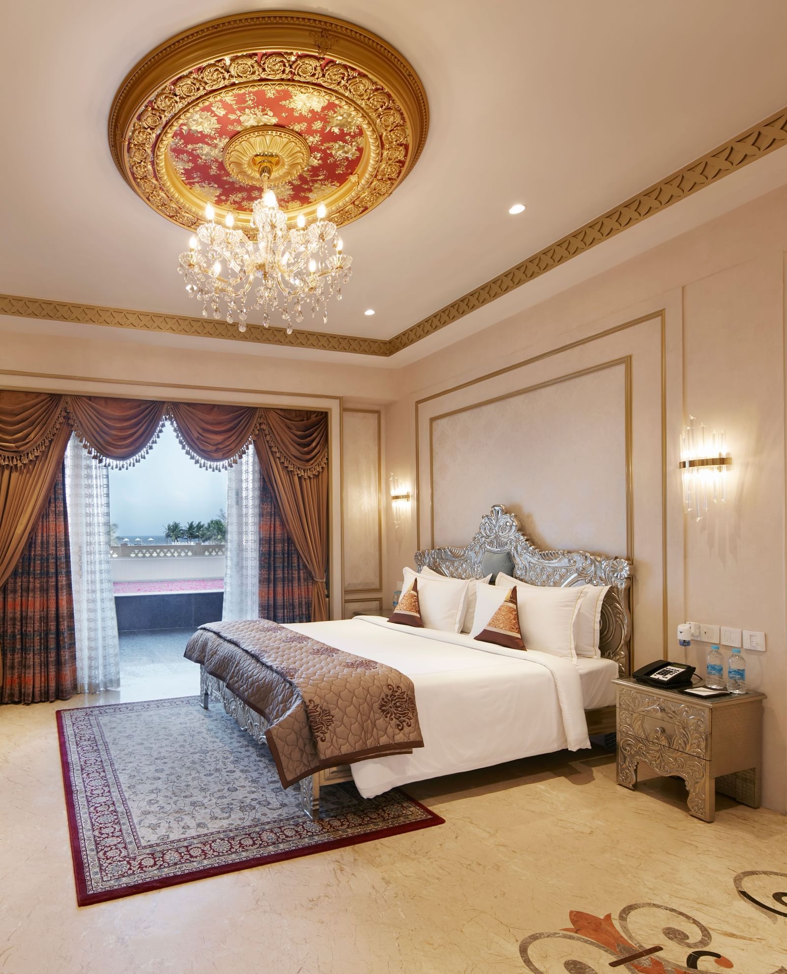 Bedroom with a regal gold-accented ceiling and a comfy double bed with red cushions - Kaldan Samudhra