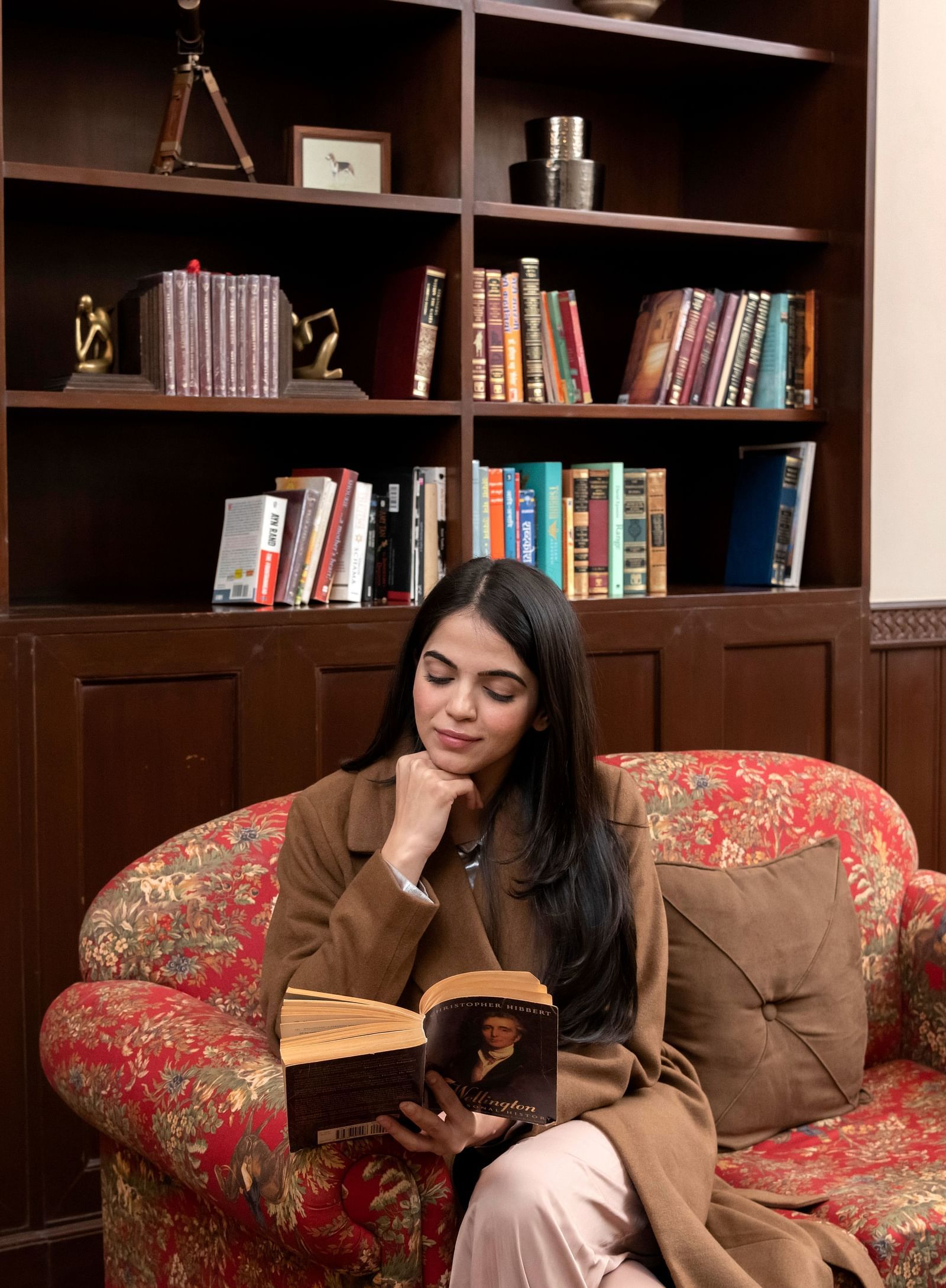 image of a woman reading a book at the library The Claridges Nabha Residence