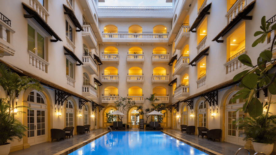 Outdoor swimming pool surrounded by the hotel buildings and arched balconies at Central Mansions, Phnom Penh.