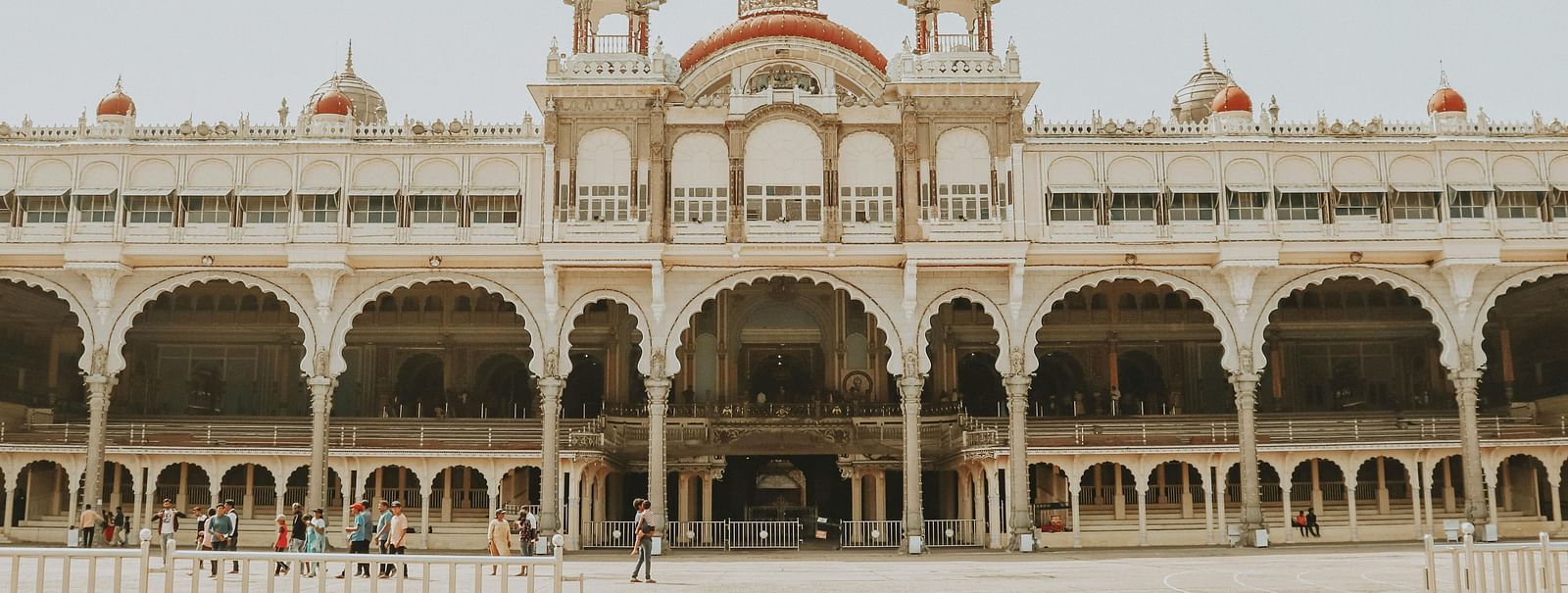 A facade image of the Mysore Palace where people are walking around in front of the structure