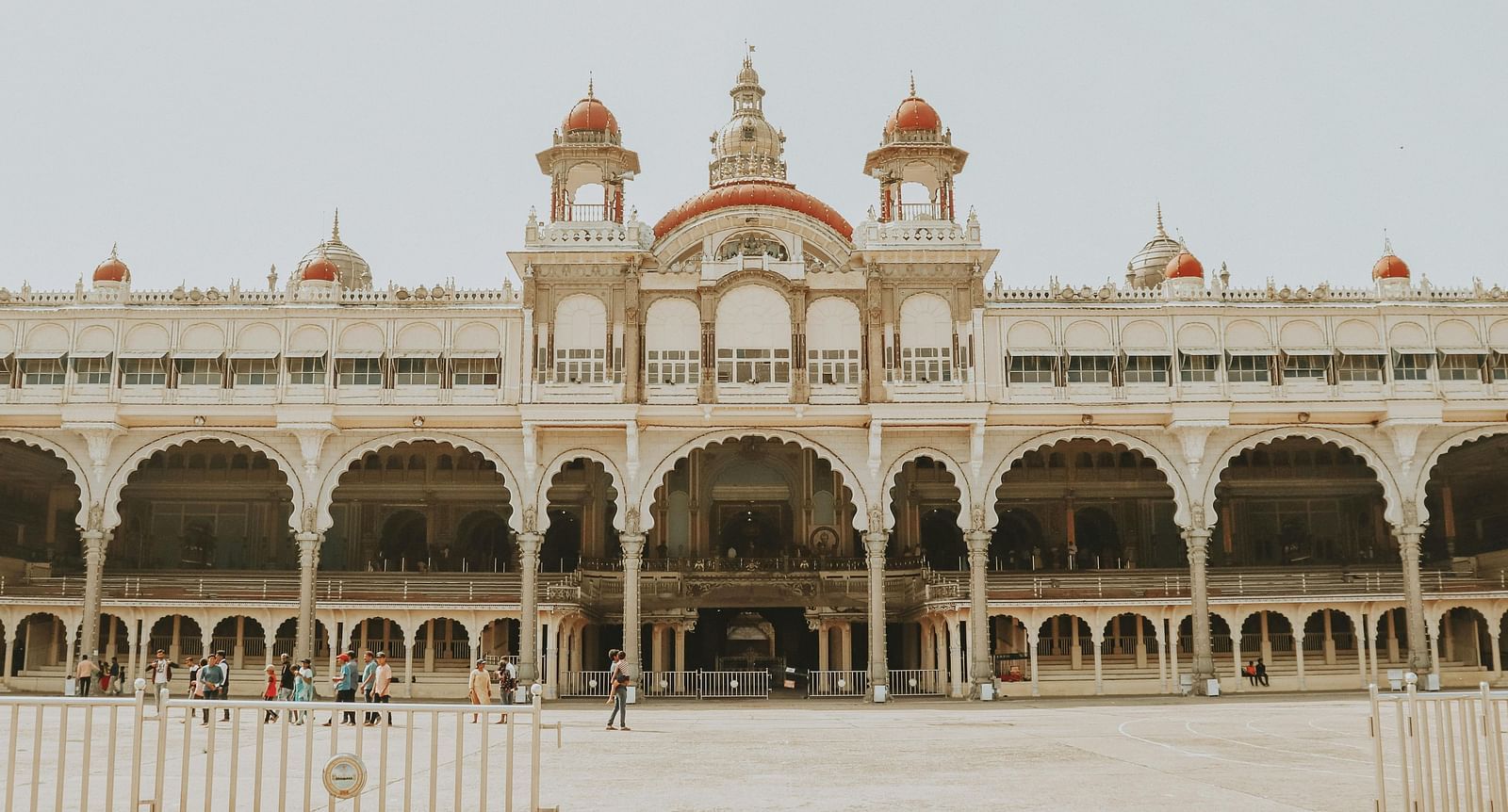 A facade image of the Mysore Palace where people are walking around in front of the structure