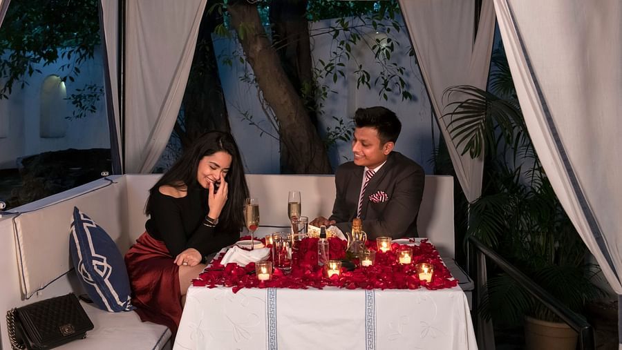 image of a couple laughing over a romantic dinner with a beautifully decorated table in an outdoor setting - The Claridges New Delhi