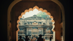 Visitors walking through an arched entrance into a grand heritage palace courtyard.