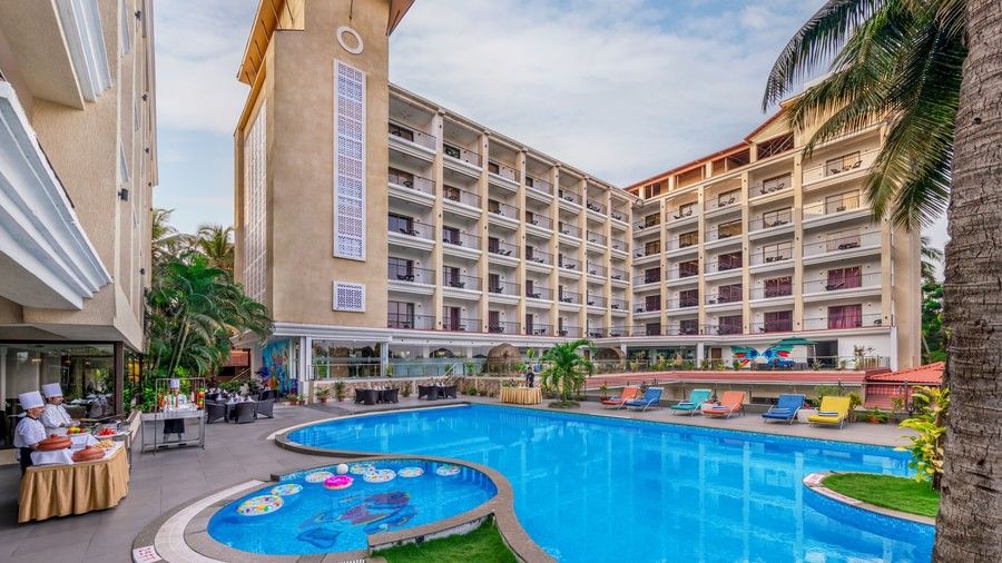 Golden Tulip, Candolim, Goa, exterior with pool, showcasing the hotel, palm trees, and a blue circular pool.