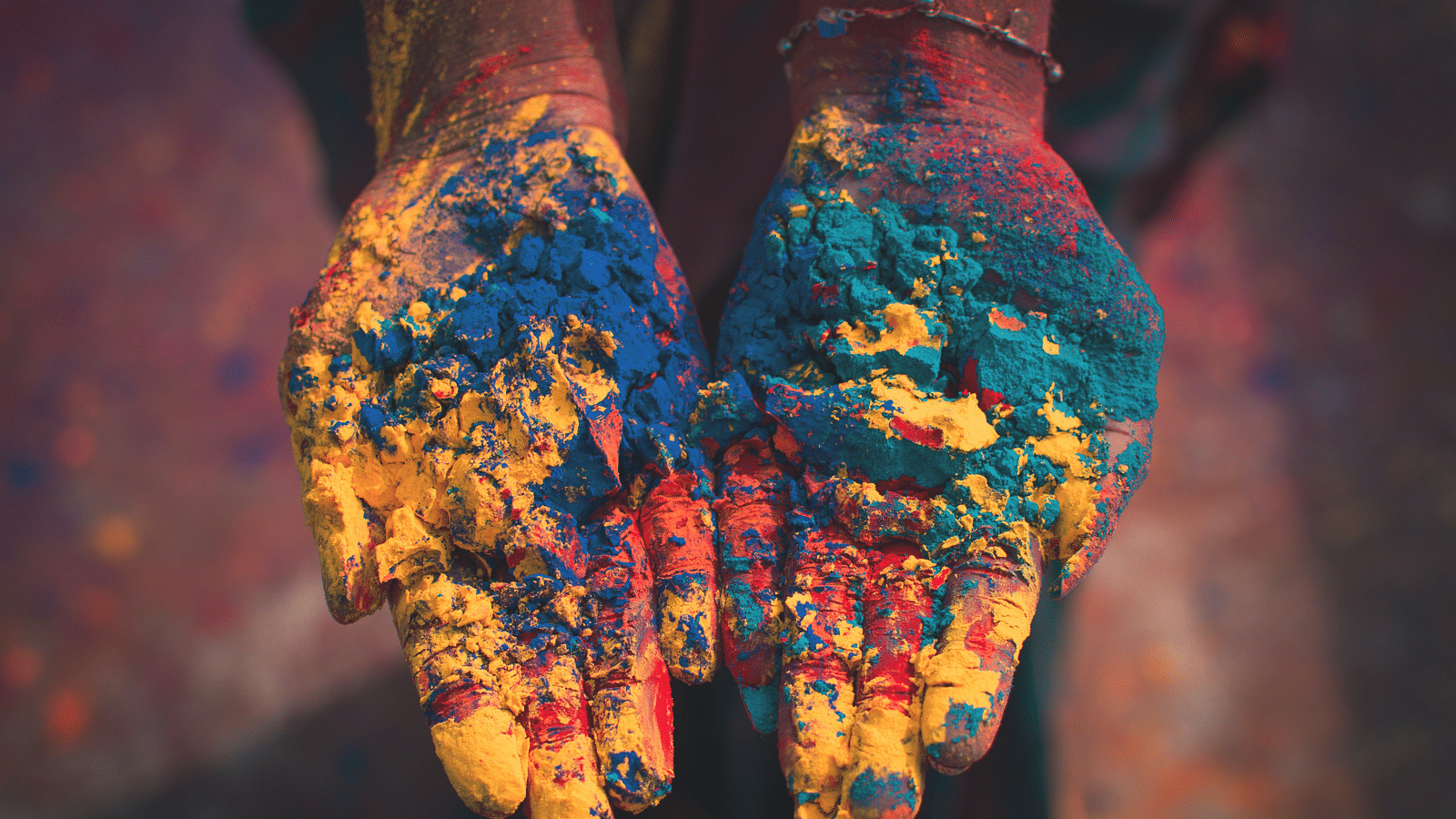 a person showing their hands with different holi colours