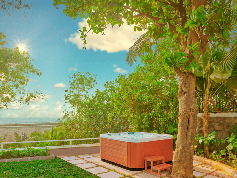 A Jacuzzi placed near a tree with a view of the ocean as seen during the day at The Resort, Mumbai.
