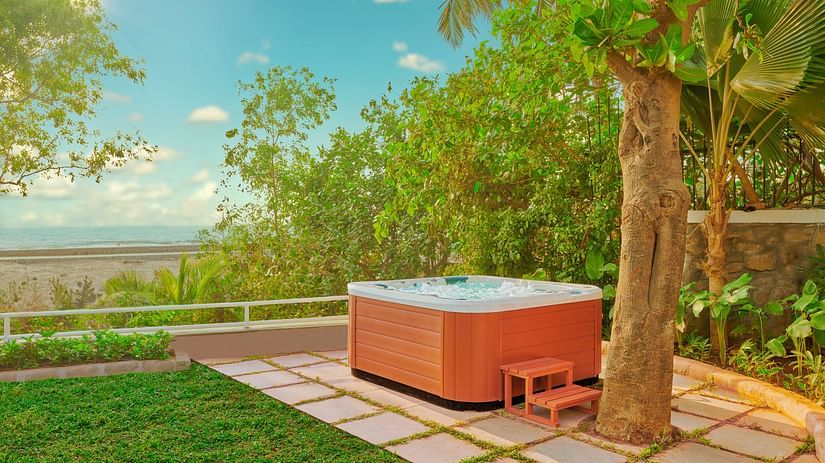A jacuzzi placed near a tree with a view of the ocean as seen during the day - The Resort, Mumbai.
