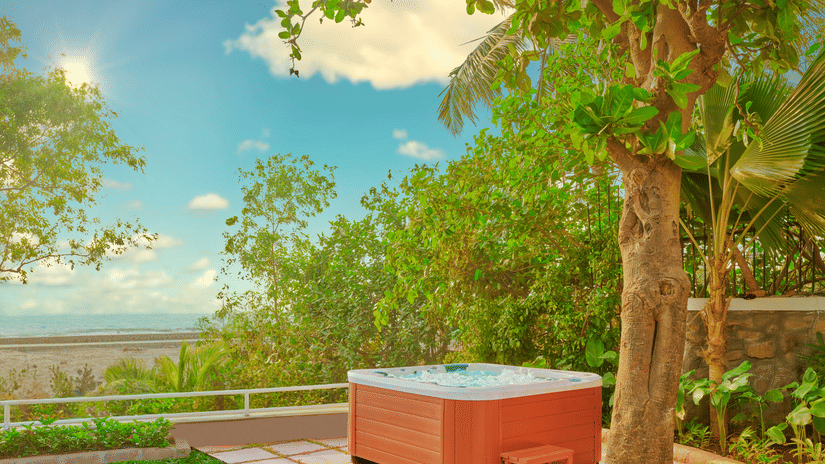A jacuzzi placed near a tree with a view of the ocean as seen during the day at The Resort, Mumbai.