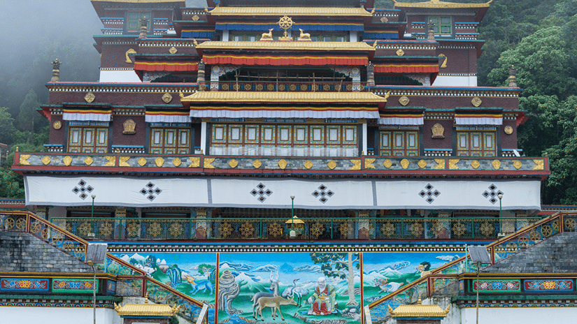 Facade of a Buddhist monastery, one of the top places to visit in Gangtok, against a lush mountain