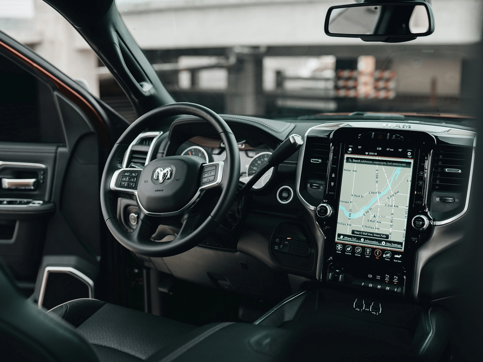 An overview of the interior of a car with steering wheel, maps and a dashboard in view