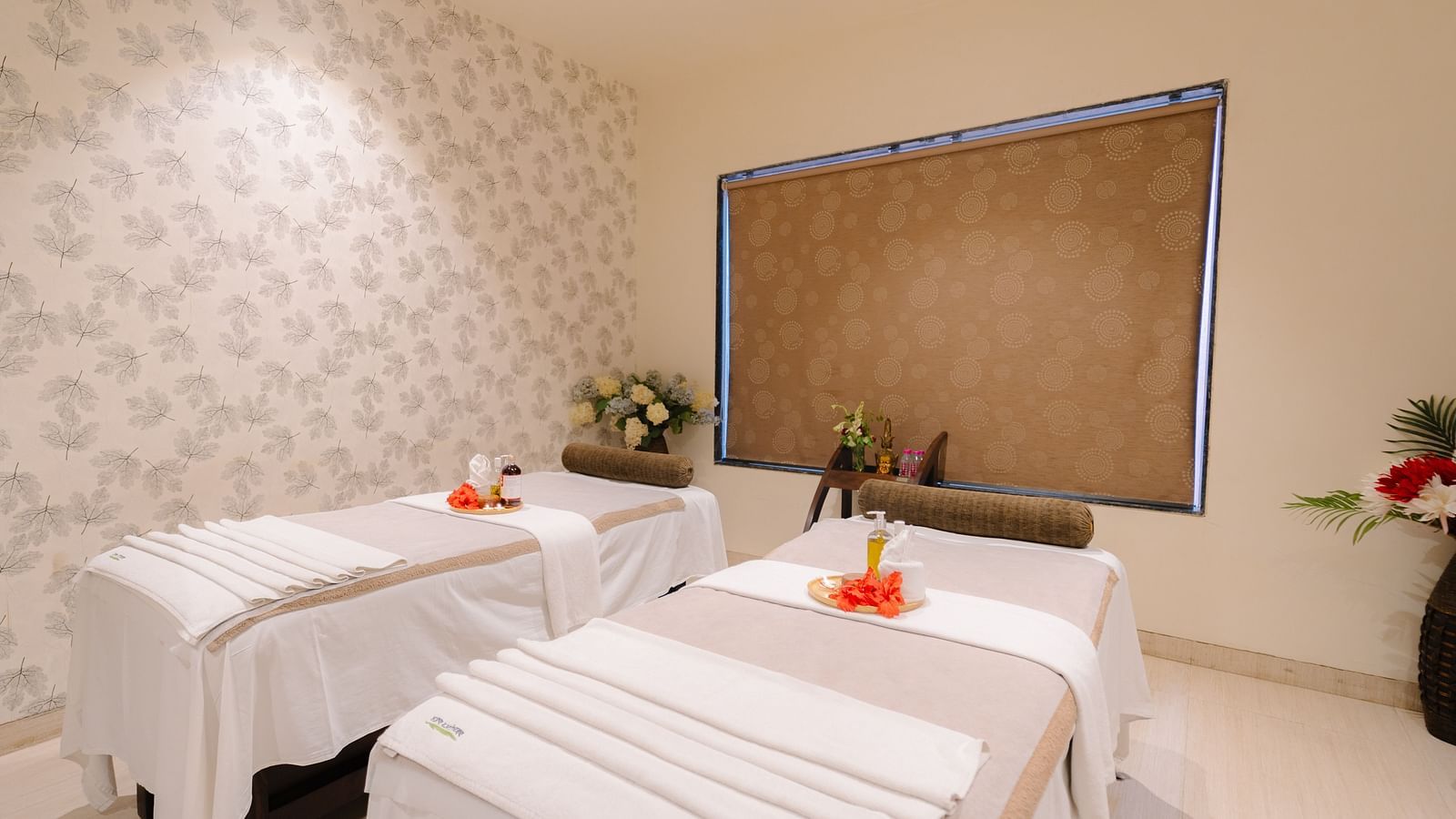Two spa beds neatly made and adorned with flowers, with all the necessary equipment arranged on the table at Crescent spa & resort, Indore