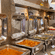 Stainless steel chafing dishes with open lids serving hot curries and gravies buffet-style at The Courtyard Restaurant, Featherlite Evoma Hotel.