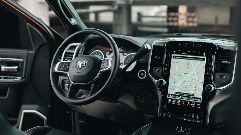 An overview of inside a car with the steering wheel, dashboard and screen in view