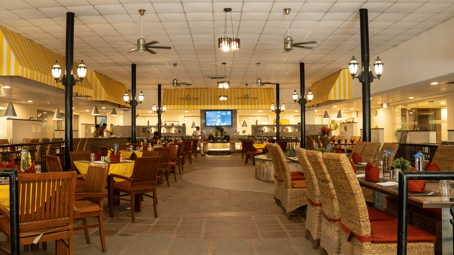 The Courtyard Restaurant at Featherlite Evoma Hotel with wooden seating, dark pillars and a wide dining hall spread throughout it.