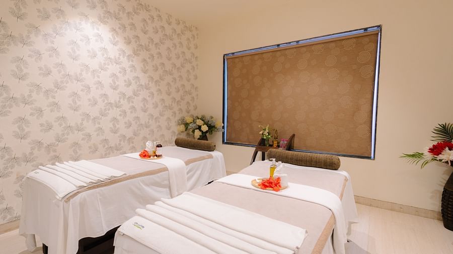 Two spa beds neatly made and adorned with flowers, with all the necessary equipment arranged on the table at Crescent spa & resort, Indore