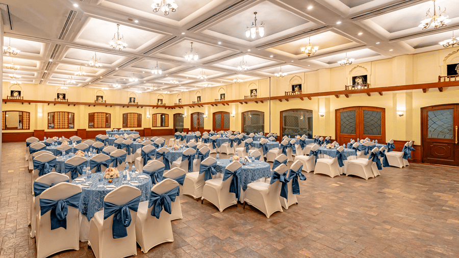A wide-angle shot of the expansive Emperor Hall at the Noor-Us-Sabah Palace, Bhopal, from the back of the hall with wooden doors and windows in the perimeter of the hall.