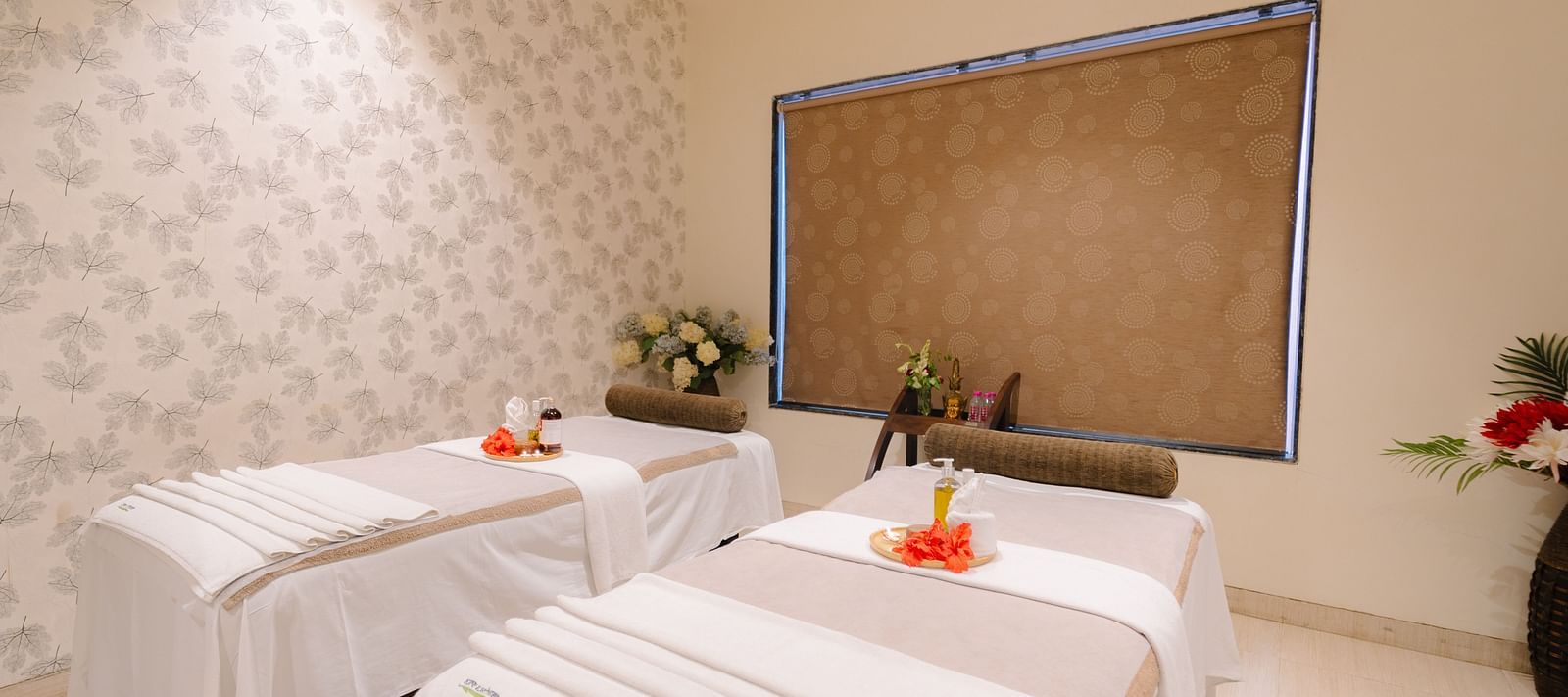 Two spa beds neatly made and adorned with flowers, with all the necessary equipment arranged on the table at Crescent spa & resort, Indore
