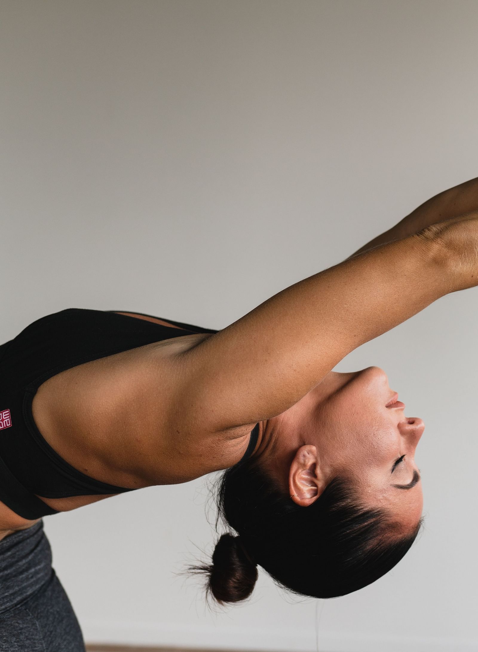 an image of a woman doing back arch stretch in front of a white wall