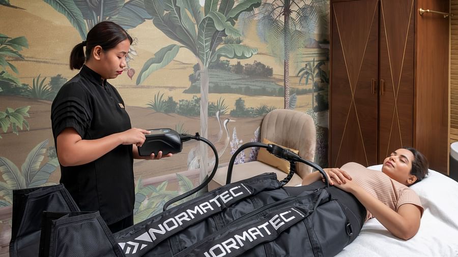 A woman administering the NORMATEC COMPRESSION THERAPY on a client at The Claridges New Delhi