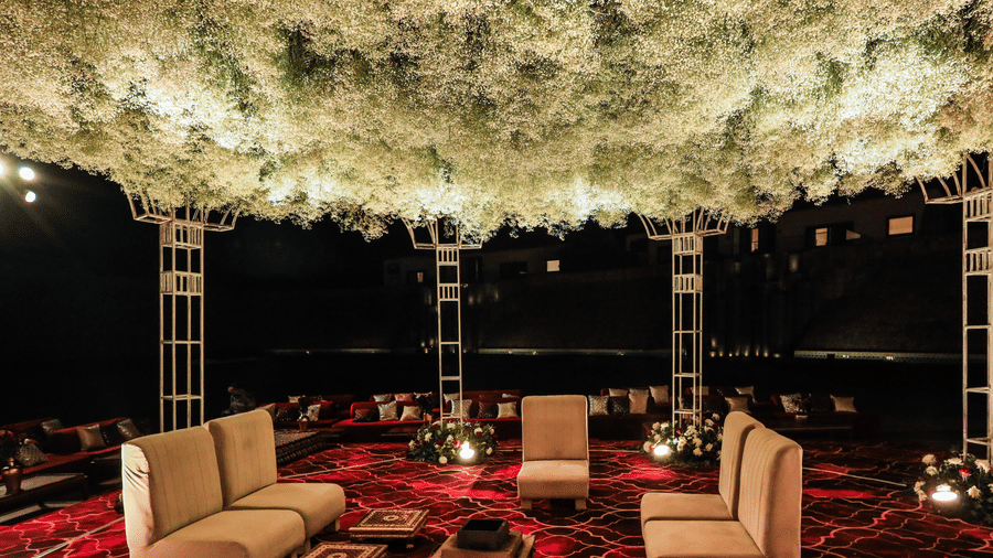 Seating area under a floral overhead setup with chairs and tables beneath at Ananta Spa & Resort, Jaipur.