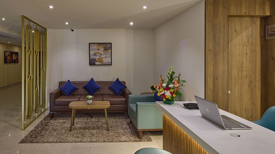 An image of a hotel lobby with a front desk and a cosy seating area with couches - Grand Continent, Brookefield
