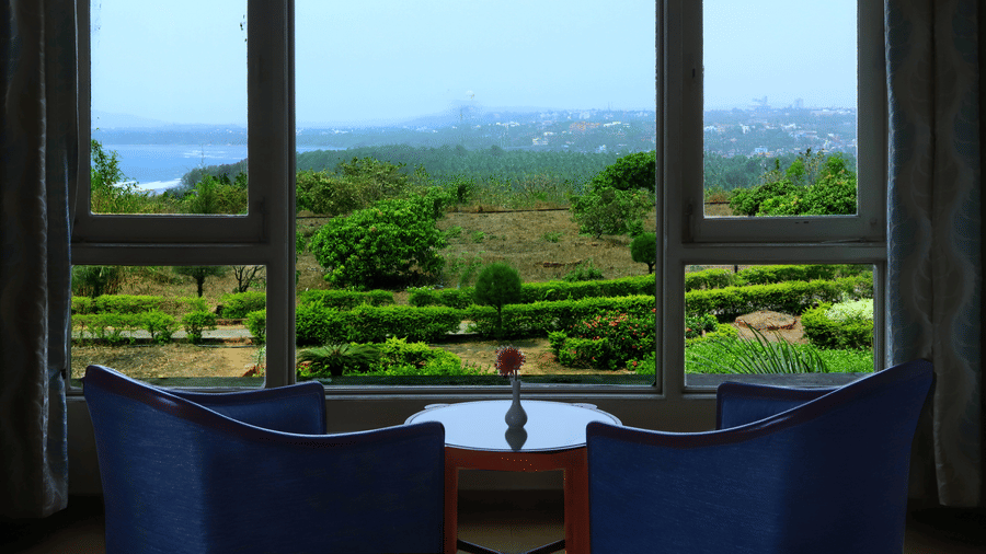 Seating area with panoramic views of lush gardens, rolling hills, and a distant waterbody at Kohinoor Samudra Beach Resort, Ratnagiri.