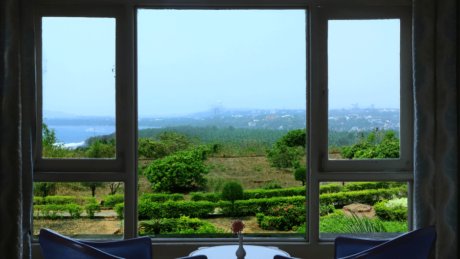 Seating area with panoramic views of lush gardens, rolling hills, and a distant waterbody at Kohinoor Samudra Beach Resort, Ratnagiri.