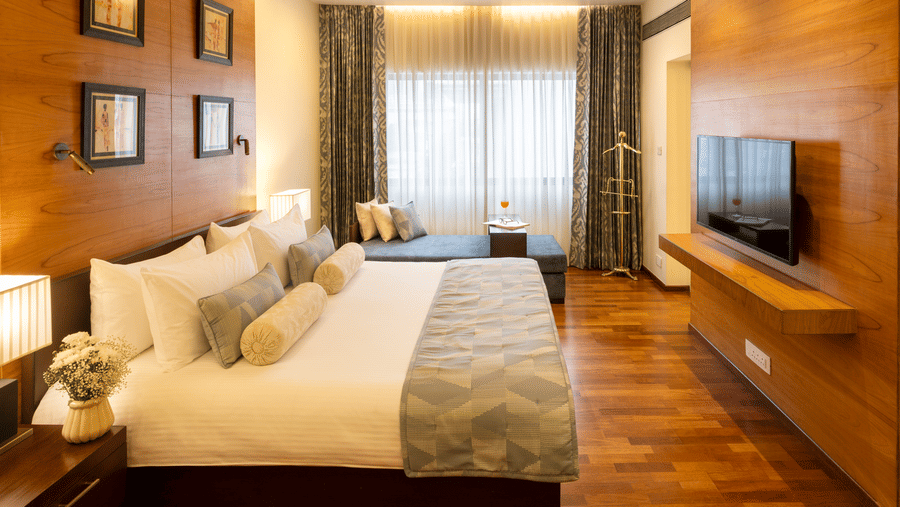 Russel Suite bedroom with a bed and wood panelled feature wall at Kenilworth Hotel, Kolkata.
