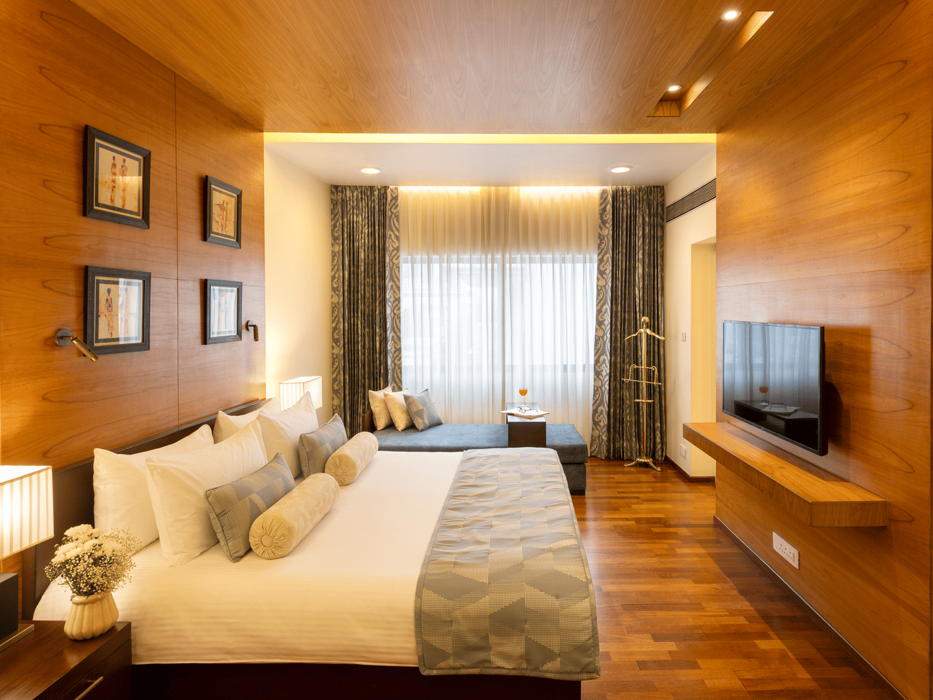 Russel Suite bedroom with a bed and wood panelled feature wall at Kenilworth Hotel, Kolkata.
