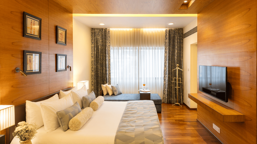 Russel Suite bedroom with a bed and wood panelled feature wall at Kenilworth Hotel, Kolkata.