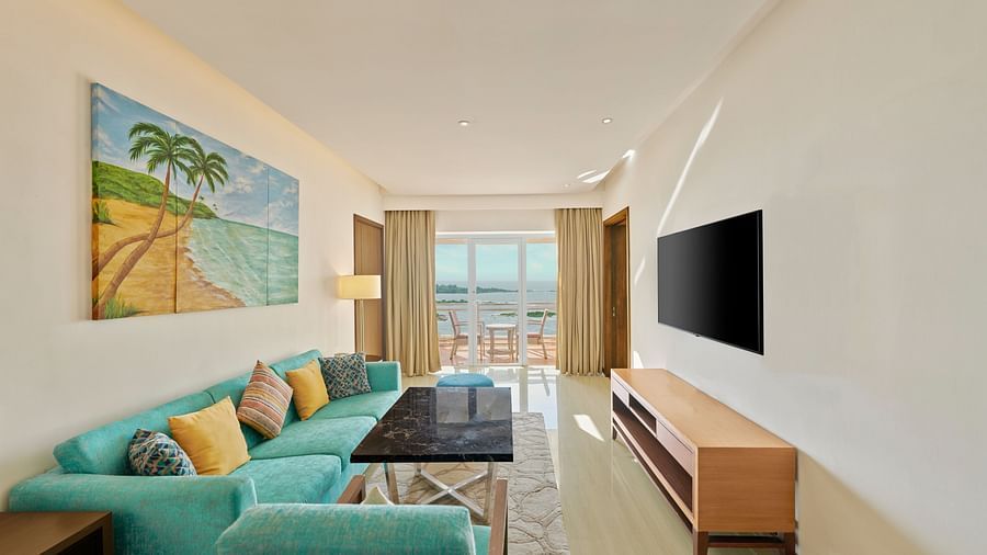 A full view of the living room with a sofa, TV and a glass window | The Resort