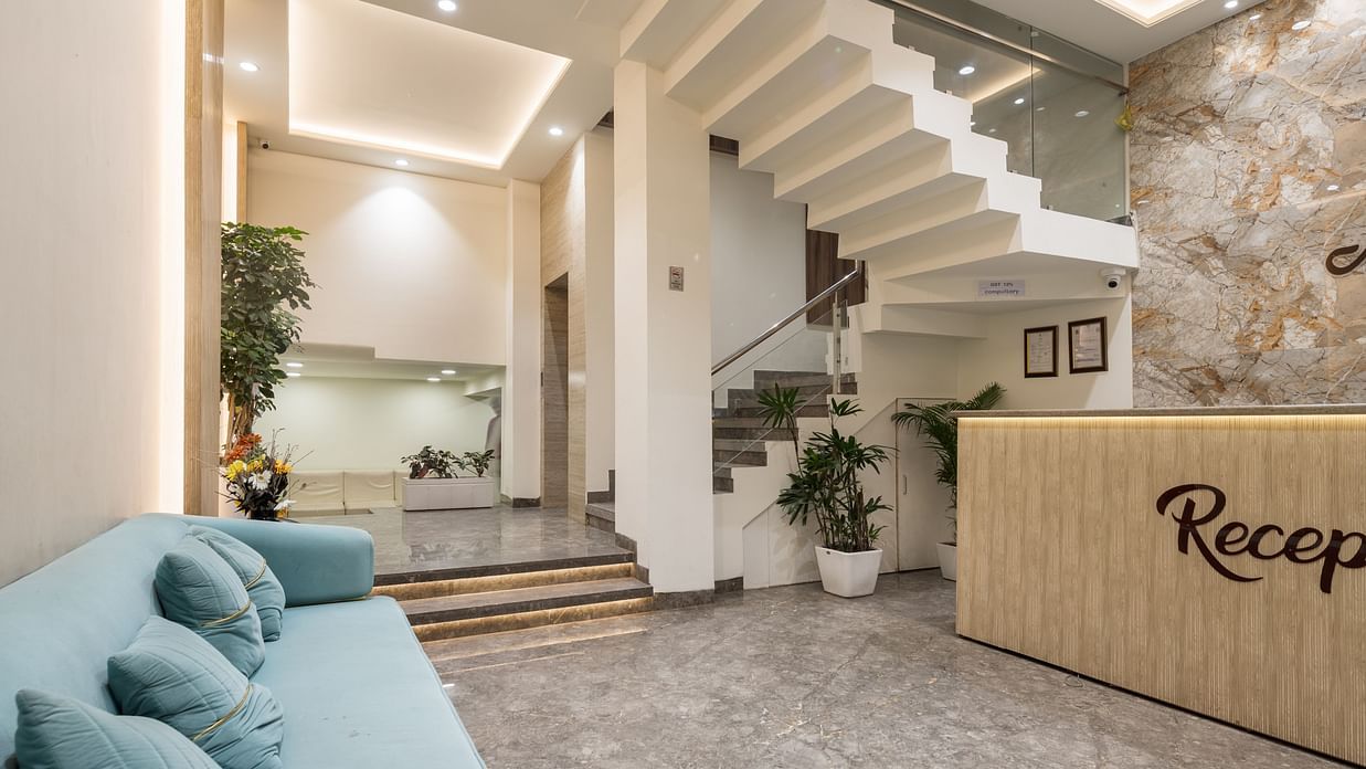 Welcoming hotel lobby at Hotel Meghdoot Bhopal showcasing modern architecture with floating staircase, comfortable seating area, natural stone accent wall, reception desk, and contemporary interior design with natural lighting