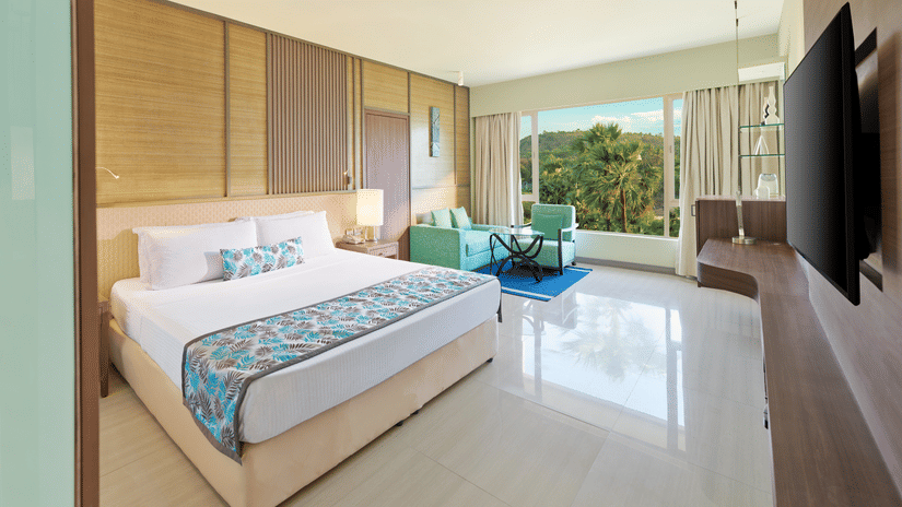 A view of the bedroom with a bed and glass window | The Resort, Mumbai.