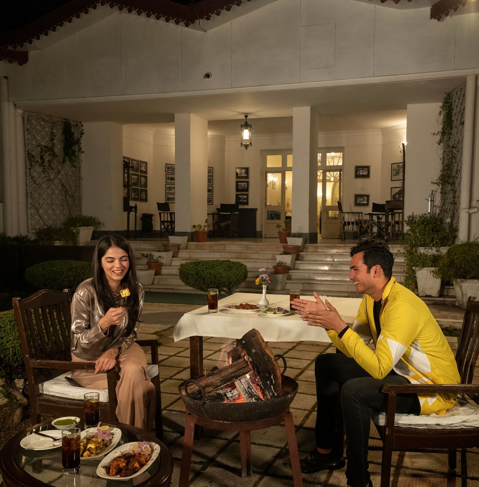 A couple enjoying a hearty laugh over dinner in a charming outdoor setting