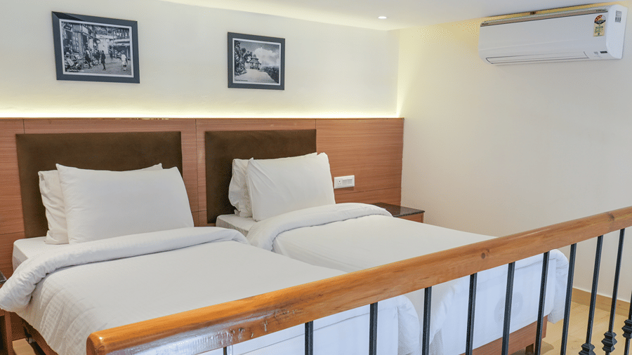 2 single beds with white bedding stand side by side behind a wooden railing at Ramada by Wyndham Mussoorie Mall Road.
