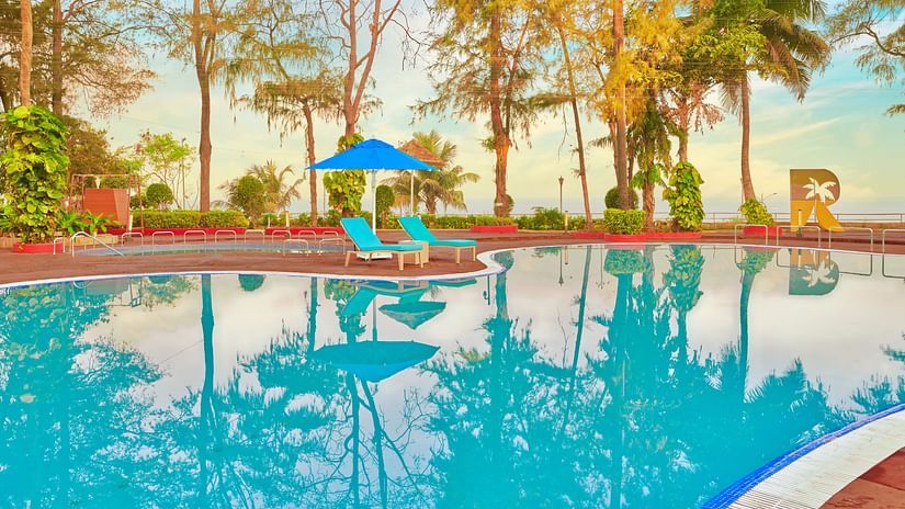 A pool surrounded by trees during the day with blue sky in the background - The Resort, Mumbai