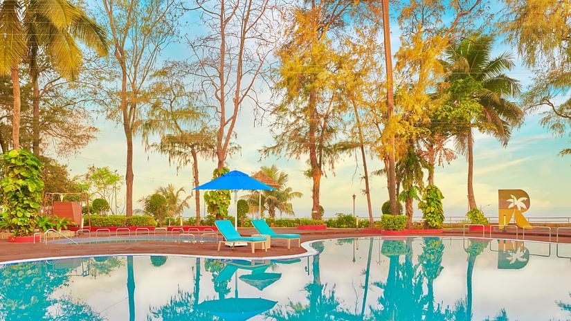 A pool surrounded by trees during the day with blue sky in the background - The Resort, Mumbai