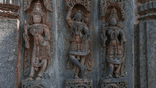 Three lady figurines carved in stone in a dancing position
