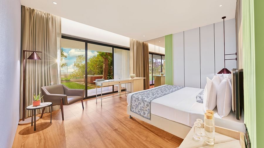 A full view of bedroom with a bed. chair and huge glass window | The Resort
