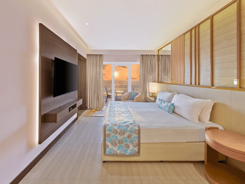 Sunset View Suite with Terrace featuring a bed facing a TV on the wall and sunset seen from the terrace at The Resort, Mumbai, best for anniversary celebration in Mumbai