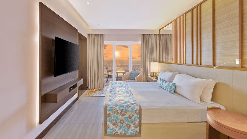 Sunset View Suite with Terrace featuring a bed facing a TV on the wall and sunset seen from the terrace at The Resort, Mumbai, best for anniversary celebration in Mumbai