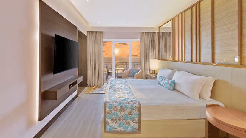Sunset View Suite with Terrace featuring a bed facing a TV on the wall and sunset seen from the terrace at The Resort, Mumbai, best for anniversary celebration in Mumbai