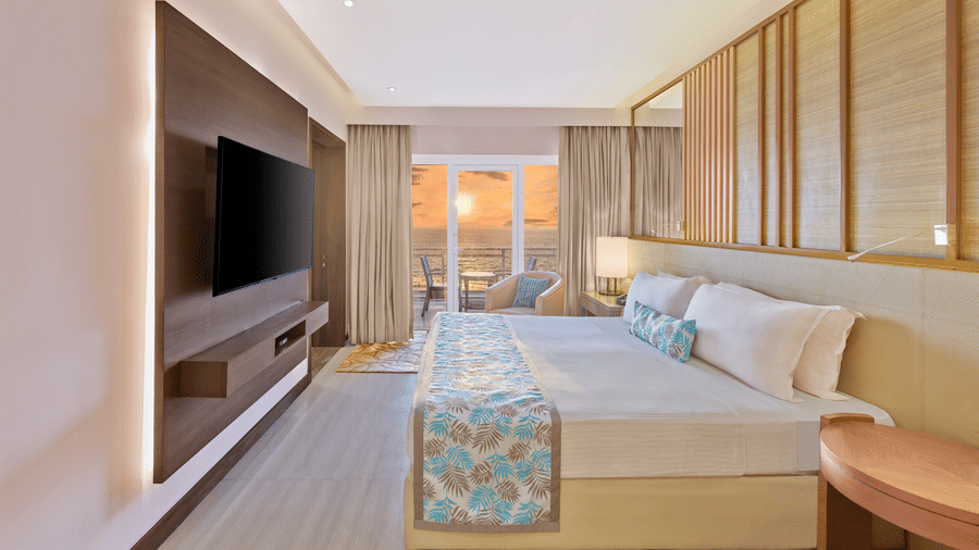 Sunset View Suite with Terrace featuring a bed facing a TV on the wall and sunset seen from the terrace at The Resort, Mumbai, best for anniversary celebration in Mumbai