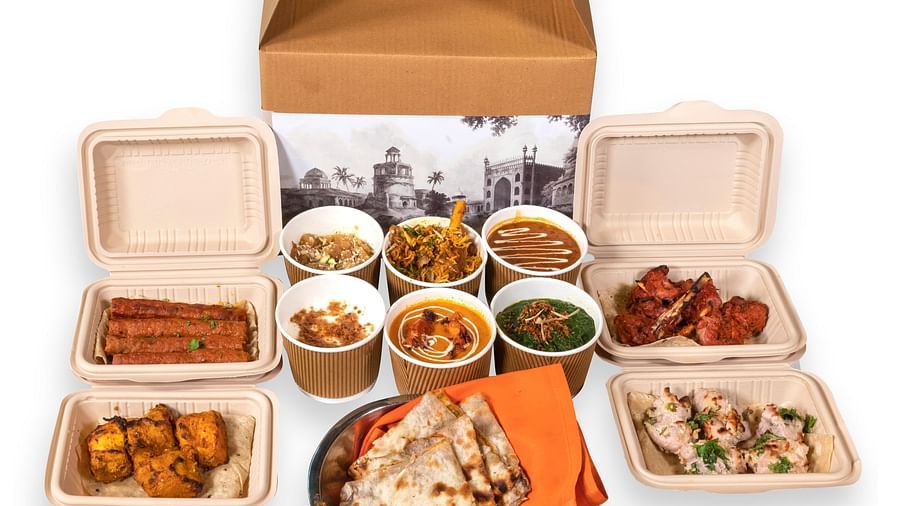 image of a whole box full of north indian delicacies with served with a type of indian bread and dips