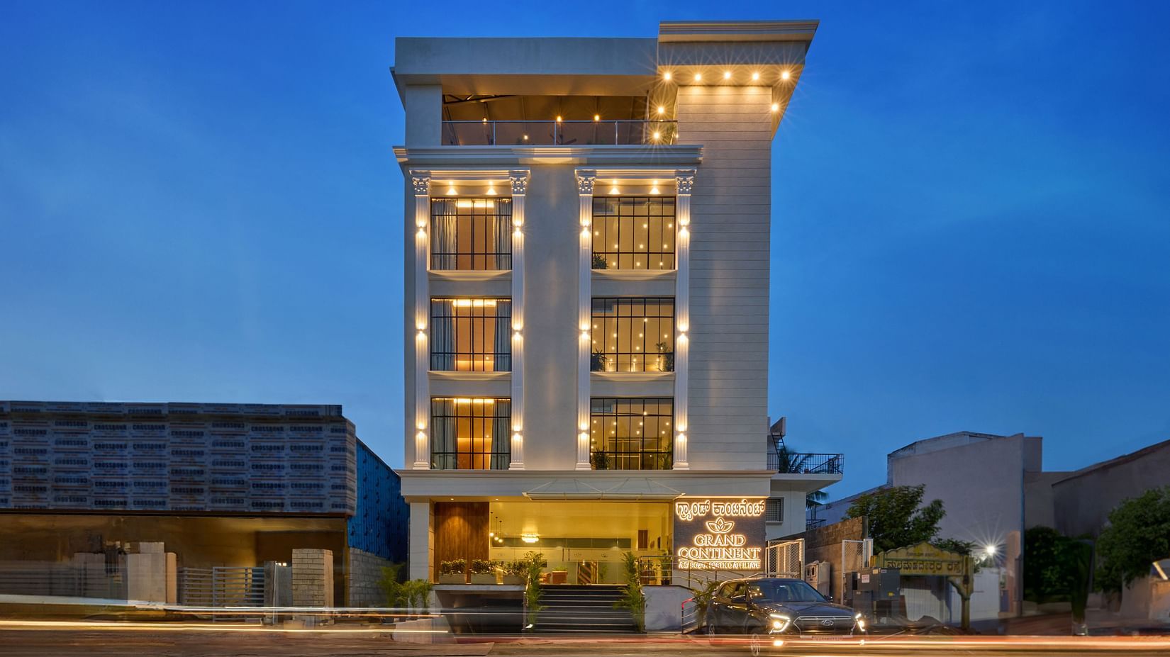 A facade image of the hotel illuminated by bright lights - Grand Continent, Mysore - A Sarovar Portico Affiliate Hotel