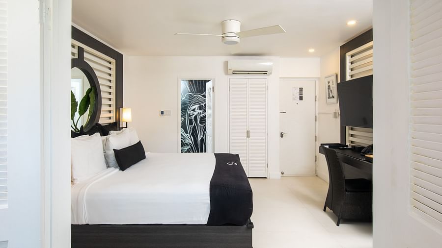 A peak into our accommodation with a large bed and a ceiling fan - S Hotel Montego Bay, Jamaica