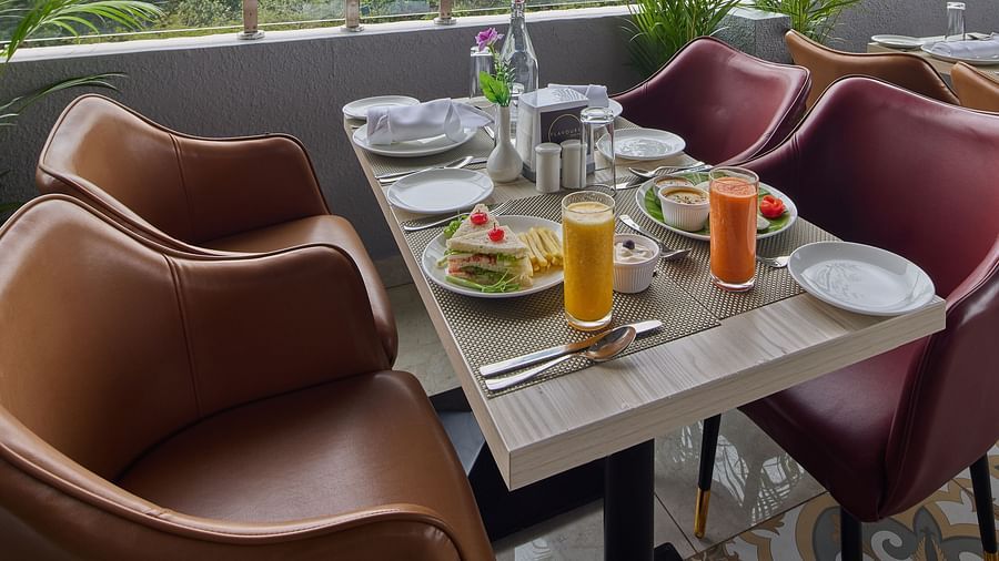 Another angle of a dining table offering a view of the lush green trees surrounding the property