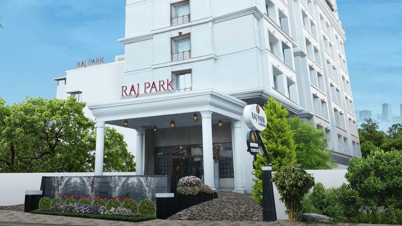 The facade of Raj Park Hotel, Chennai surrounded by greenery, with a bright sky in the background - Raj Park Hotel, Chennai