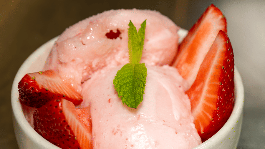 Bowl of strawberry ice cream topped with fresh strawberries and a mint leaf served as dessert at Narrow Gauge Inn.
